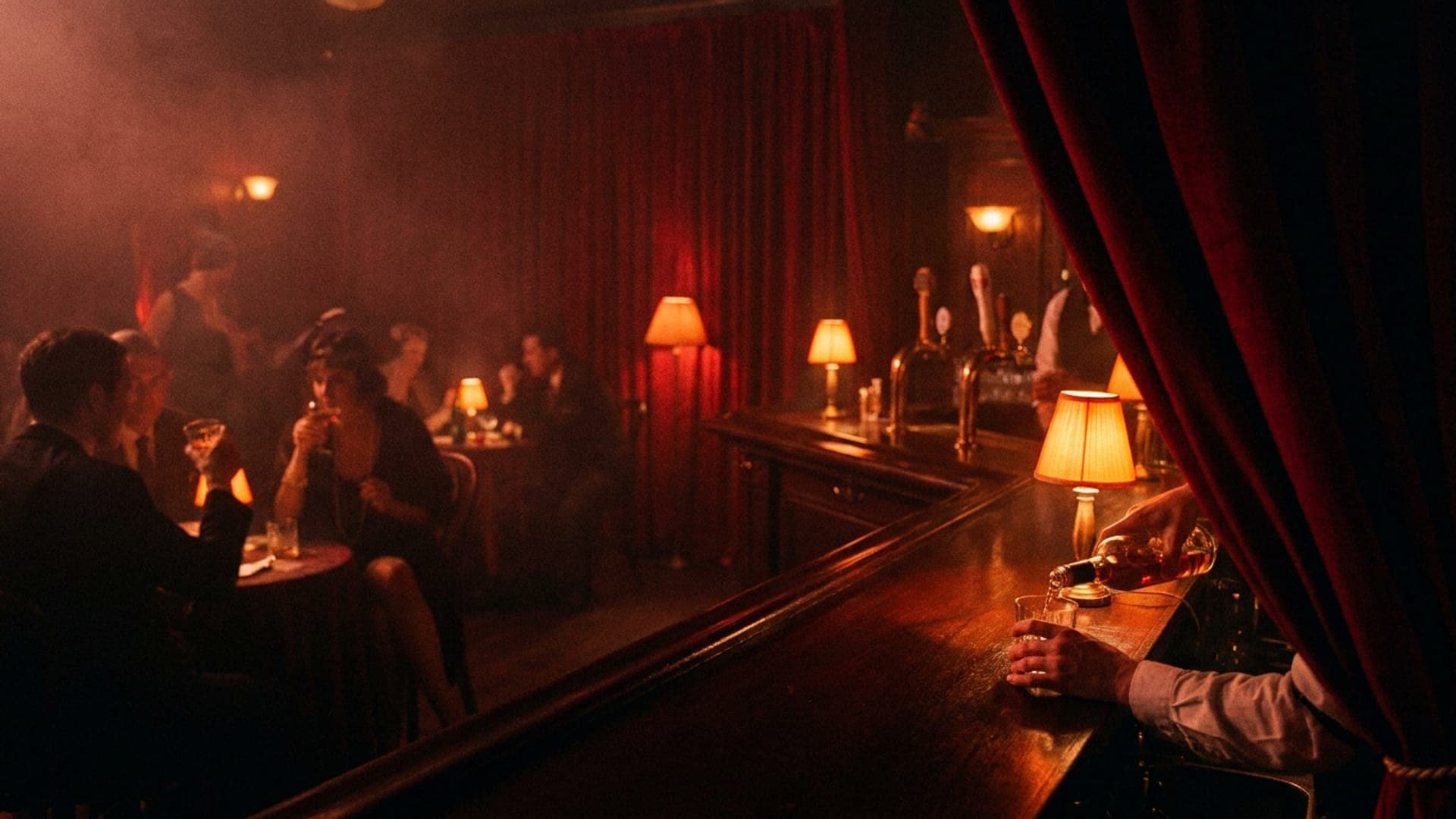 The bar at The Ravens Club under low amber lamps — a bartender pouring whiskey at the rail, guests at candlelit tables behind, red velvet curtains at the back